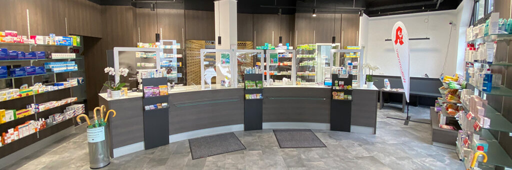 Innenansicht Verkaufsraum Delta-Apotheke, hohe Wandregale mit Arzneimitteln in halbrundem Raum, davor ein Verkaufstresen